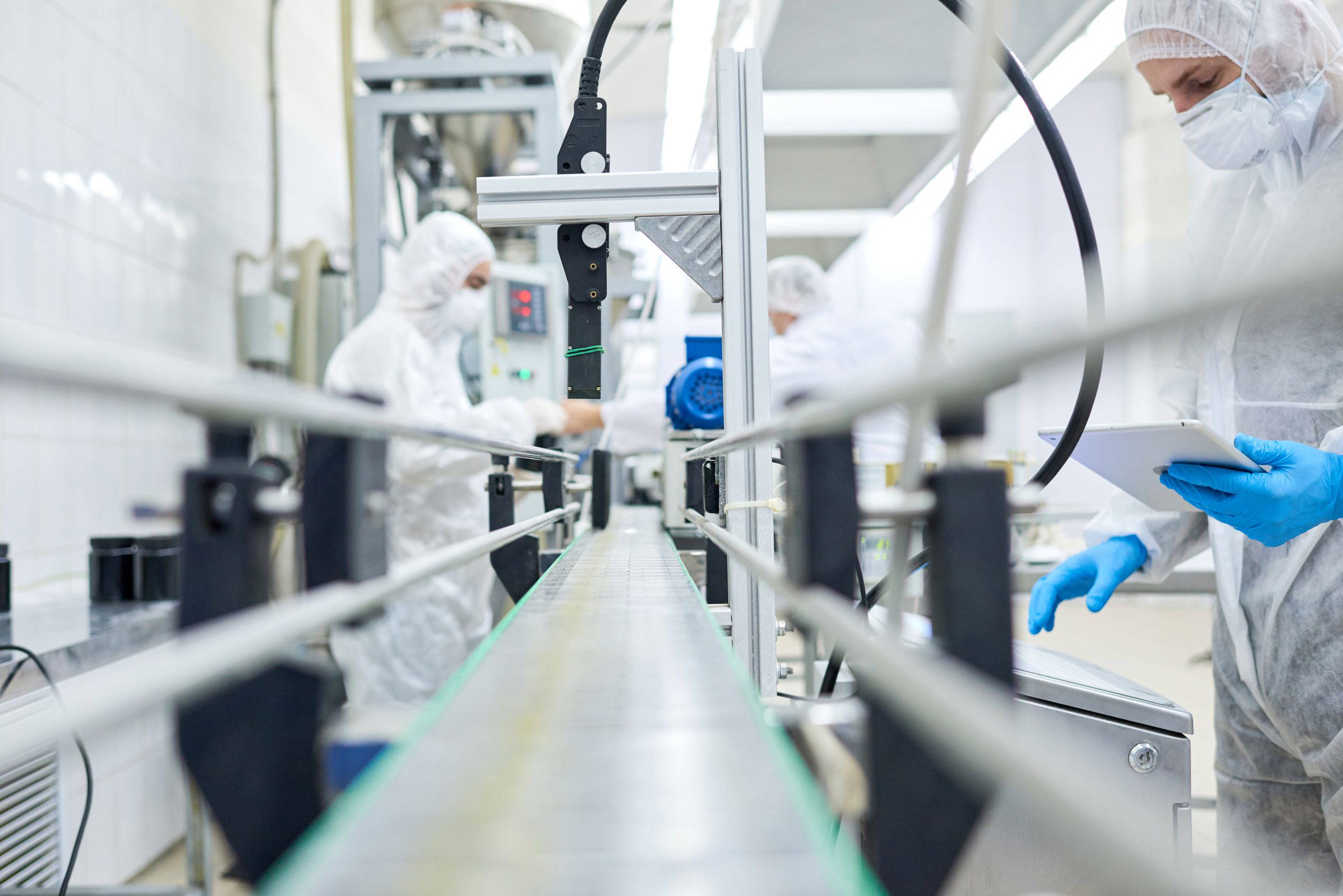 Factory workers standing at conveyor belt